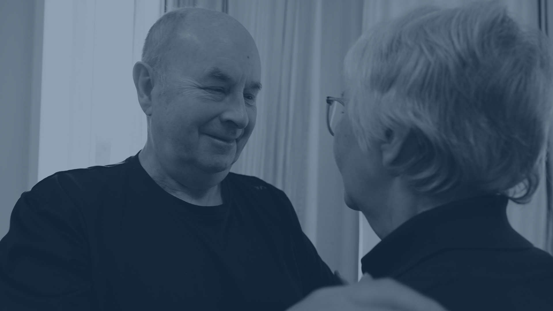 An elderly couple dancing at home with an Ode speaker nearby